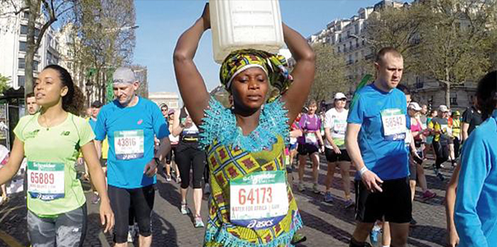 Woman carries can of water on her head along Paris marathon